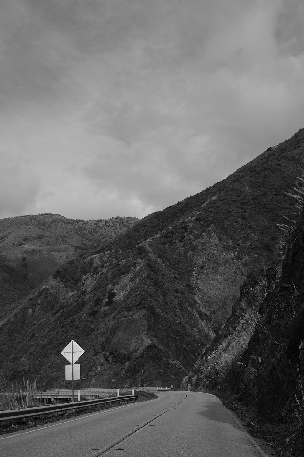 Black and white portrait photo of the Pacific Coast Highway winding through mountain canyons.