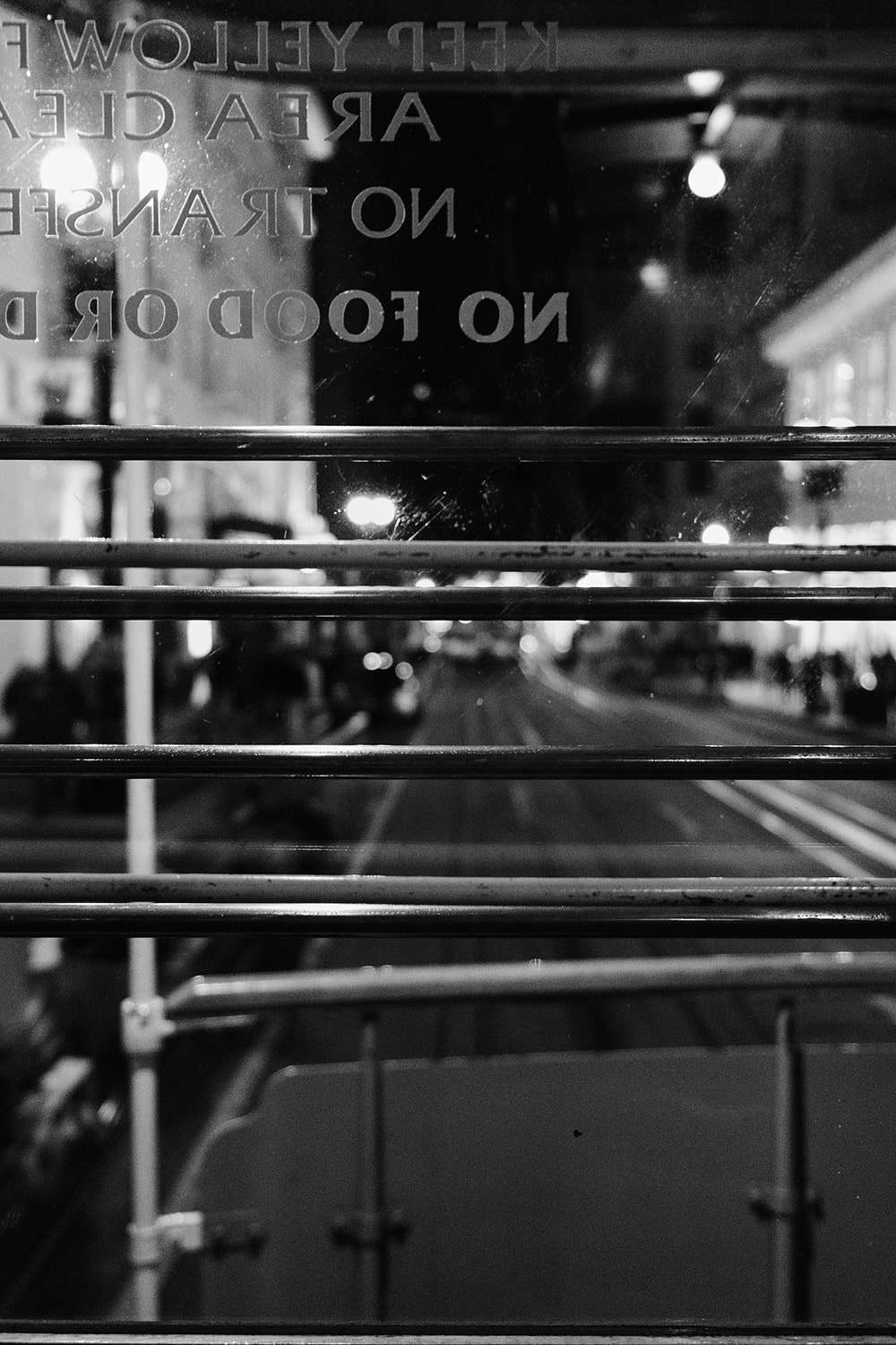 Black and white portrait photo through the back window of a cable car. The street and cable line disappearing down the street.