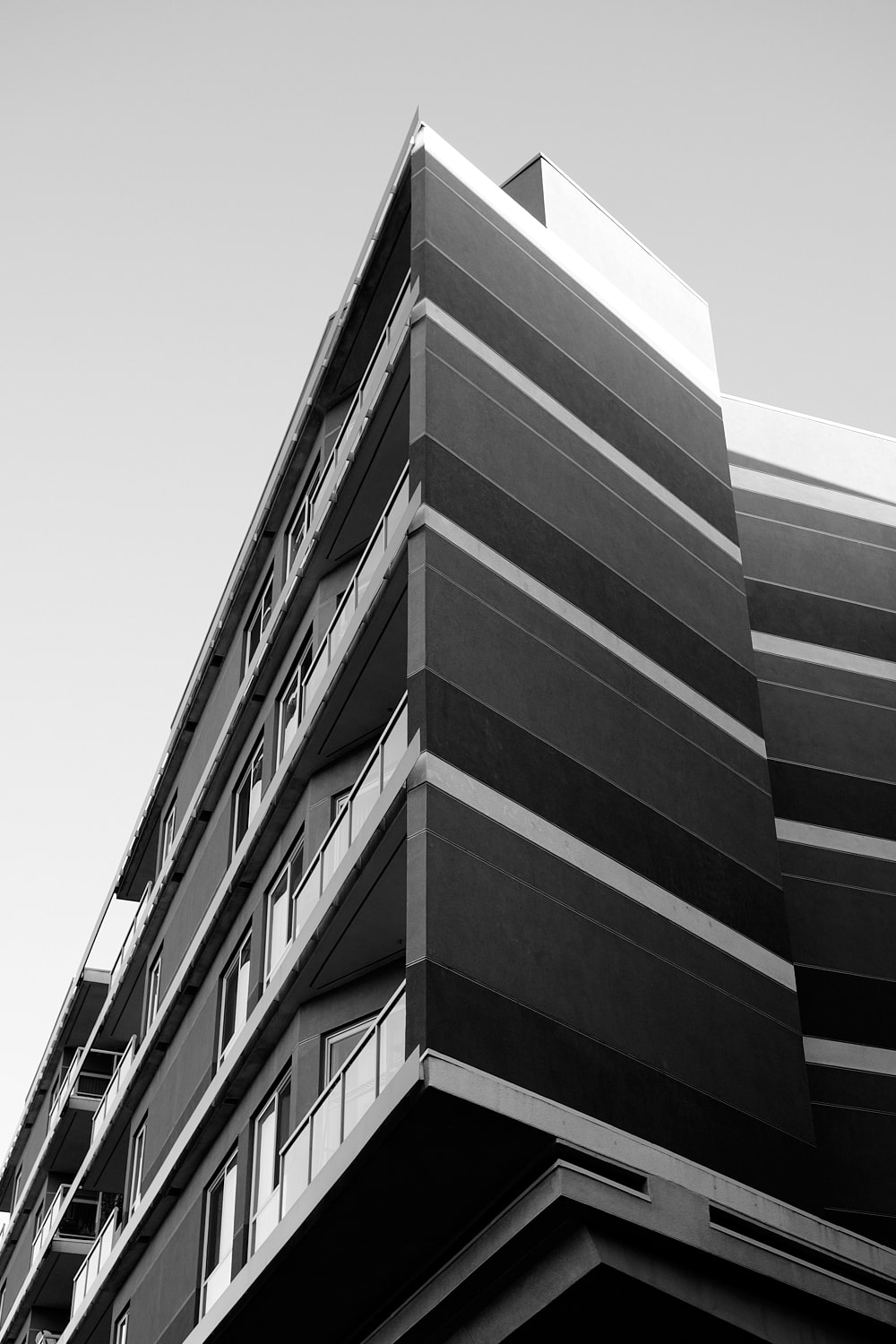 Black and white portrait photo highlighting the vertical angles and multiple colored facade of an apartment building.