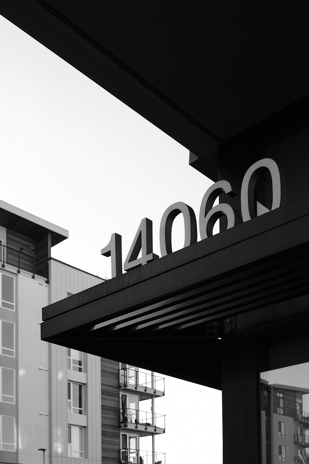Black and white portrait photo of the overhead address sign for 14060 apartment building.