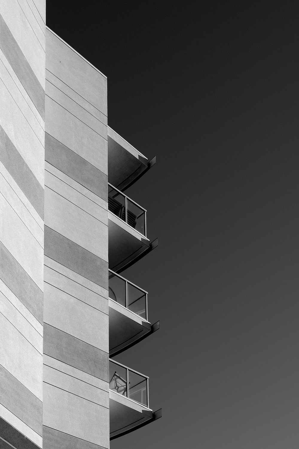 Black and white portrait photo of balconies hanging off the side of an apartment building.