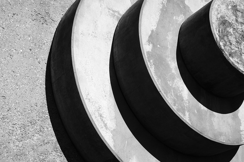 Black and white landscape photo of Venice beach outdoor gym. This photo is an abstract close up shot of the large concrete weights on the side of the building.